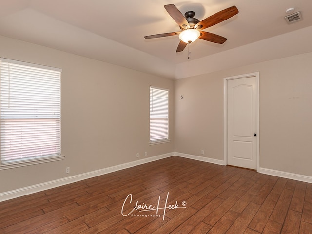 empty room featuring dark wood-style floors, visible vents, ceiling fan, and baseboards