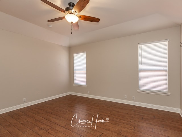 spare room featuring a ceiling fan, baseboards, and dark wood-style flooring