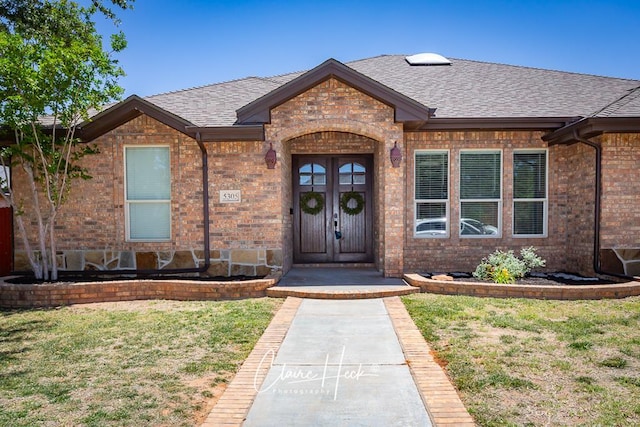5305 Wimberley Spring Ct, Midland, TX 79707 - view of exterior entry with a shingled roof, brick siding, and a lawn