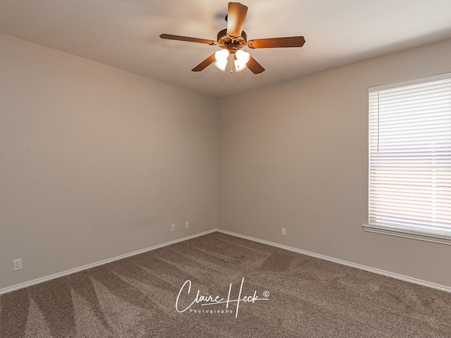 empty room featuring baseboards, dark carpet, and a ceiling fan