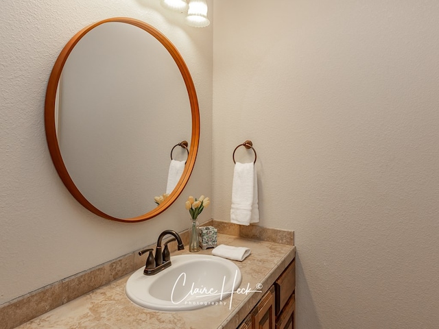 bathroom with a textured wall and vanity