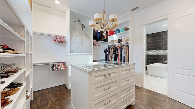 spacious closet featuring dark hardwood / wood-style flooring and a chandelier