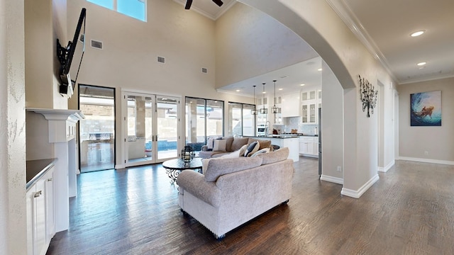 living room featuring dark wood-type flooring, ornamental molding, french doors, and a high ceiling