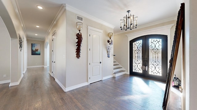 foyer entrance with french doors, crown molding, a chandelier, and dark wood-type flooring