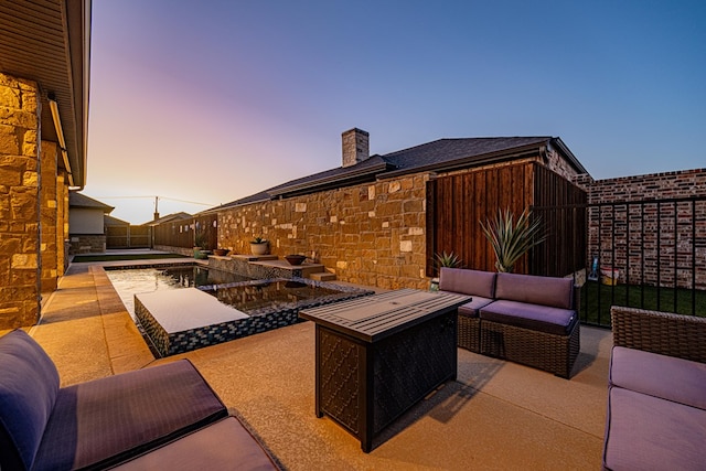 patio terrace at dusk with an outdoor living space with a fire pit