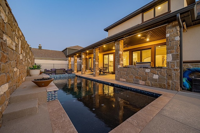 pool at dusk featuring a patio area