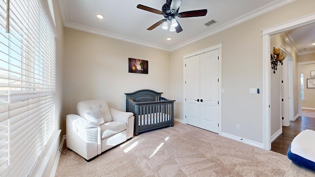 bedroom with crown molding, ceiling fan, carpet, and a closet