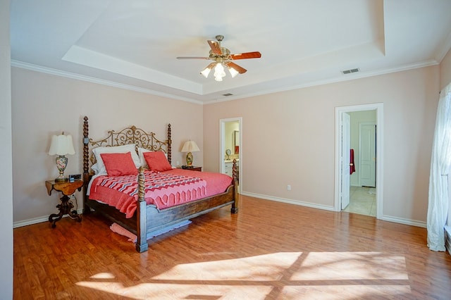 bedroom with a tray ceiling, wood finished floors, and baseboards