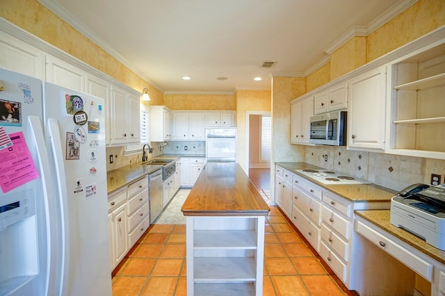 kitchen with white cabinets, butcher block counters, appliances with stainless steel finishes, open shelves, and a sink