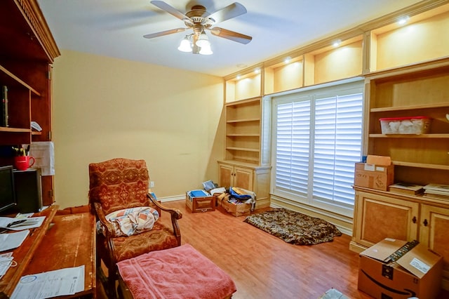 living area featuring built in features, wood finished floors, a ceiling fan, and baseboards