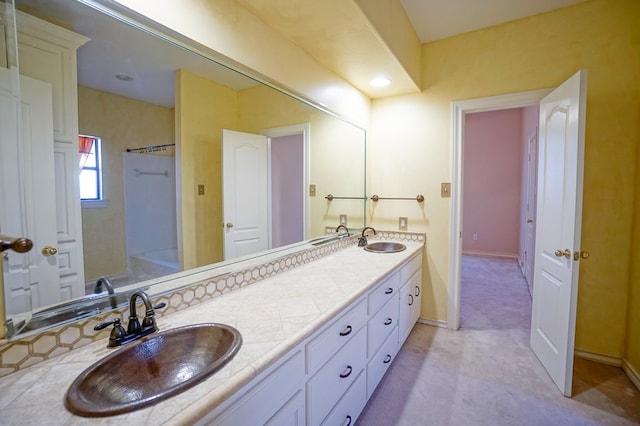 full bath with double vanity, baseboards, and a sink