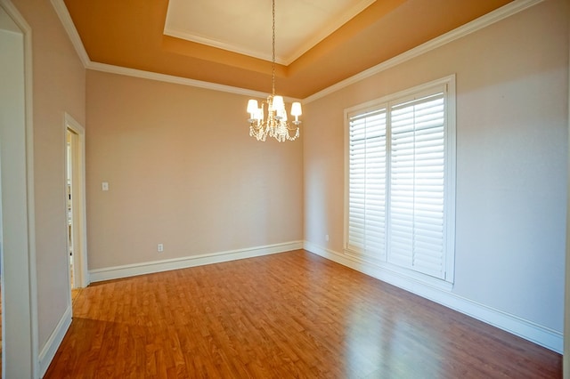 spare room with baseboards, a chandelier, a raised ceiling, and wood finished floors