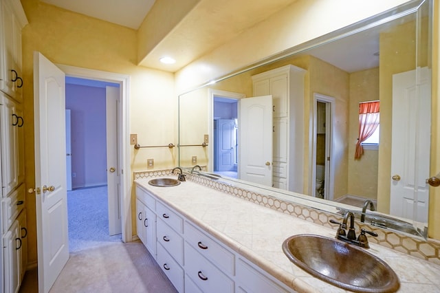 bathroom with double vanity, toilet, and a sink