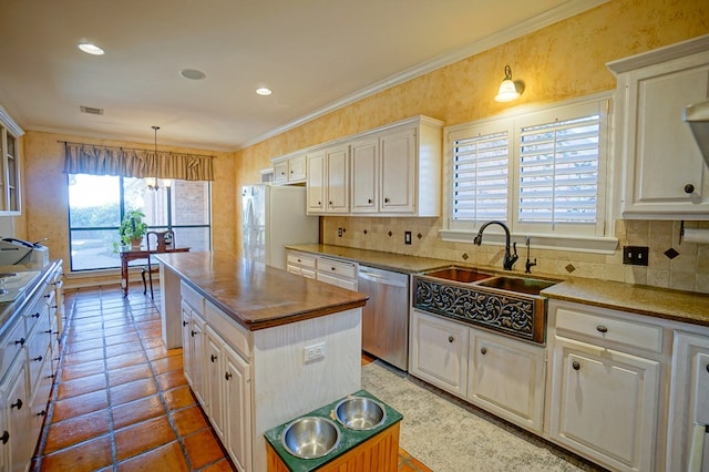 kitchen featuring a center island, decorative light fixtures, stainless steel dishwasher, ornamental molding, and freestanding refrigerator