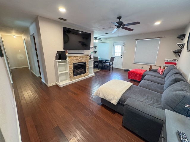 living area featuring visible vents, a fireplace, dark wood finished floors, and a ceiling fan