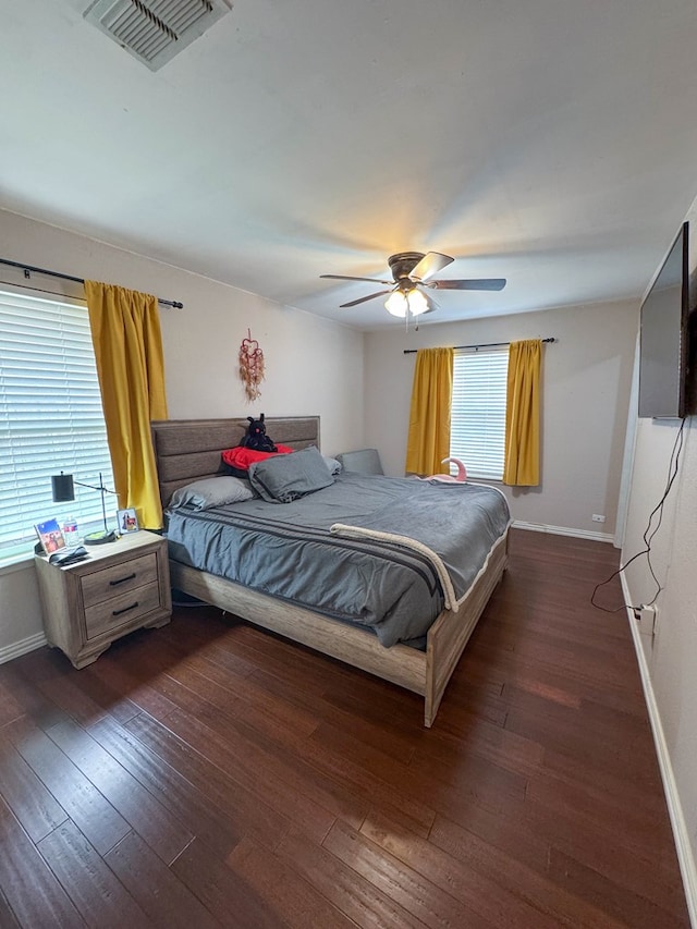 bedroom featuring dark wood finished floors, visible vents, a ceiling fan, and baseboards