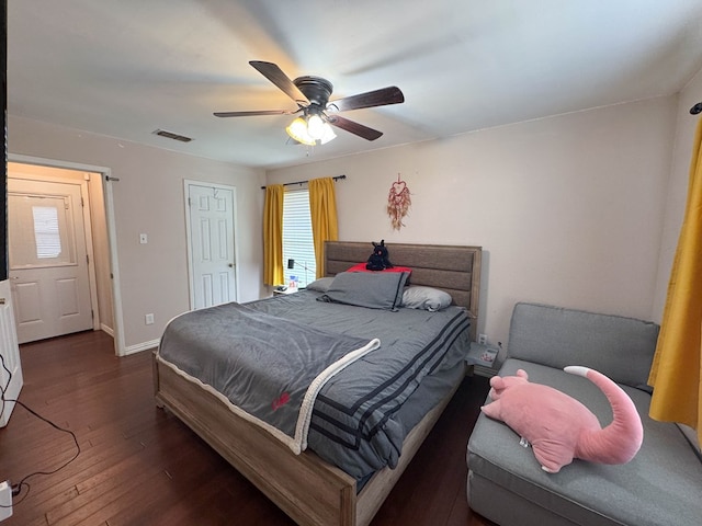 bedroom featuring ceiling fan, visible vents, baseboards, and wood finished floors