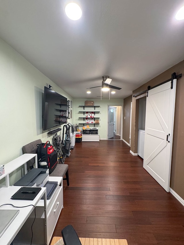 interior space with a barn door, baseboards, hardwood / wood-style floors, and a ceiling fan