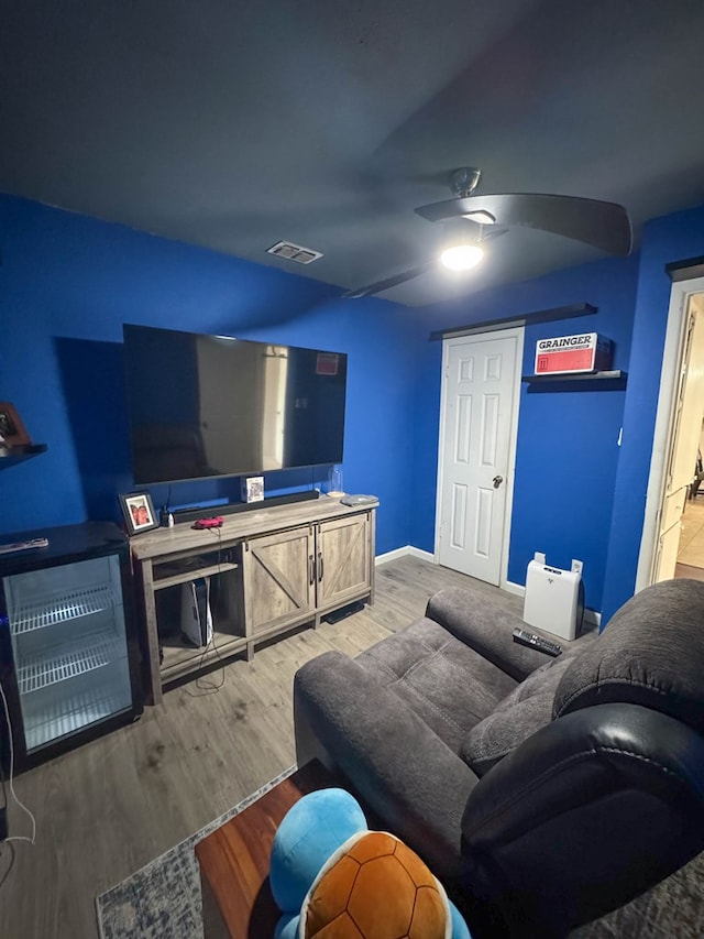 living area with baseboards, visible vents, a ceiling fan, and light wood-style floors