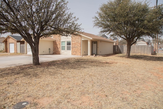 ranch-style home featuring concrete driveway, an attached garage, fence, and brick siding