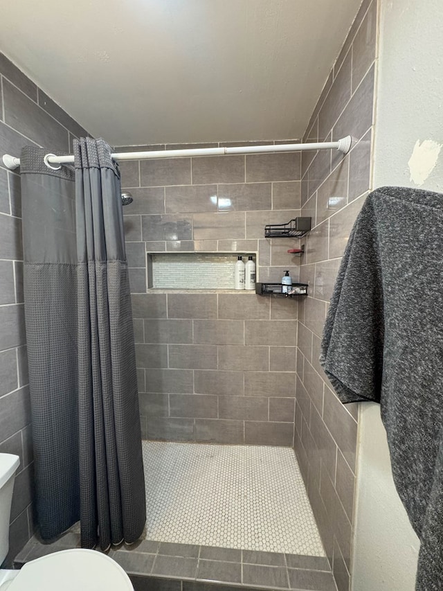 bathroom featuring toilet and a tile shower