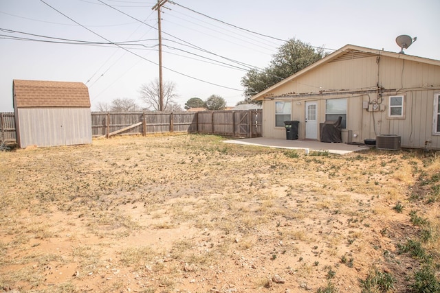 view of yard featuring an outbuilding, a fenced backyard, a storage unit, and a patio