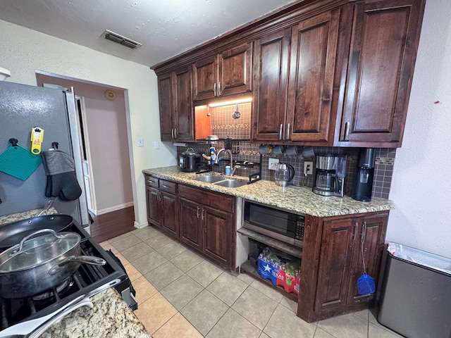 kitchen with visible vents, a sink, tasteful backsplash, stainless steel appliances, and light tile patterned flooring