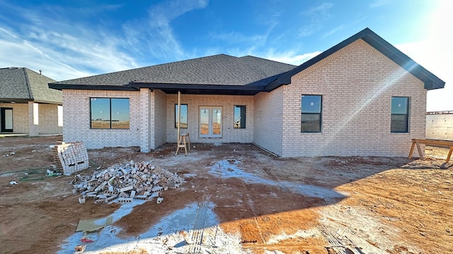 rear view of property with french doors, brick siding, and a shingled roof