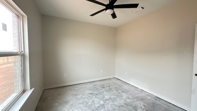 unfurnished room with unfinished concrete floors, a ceiling fan, and baseboards