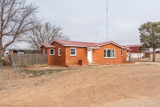 1204 Tinker St, Seagraves, TX 79359 - view of front facade featuring metal roof, brick siding, and fence