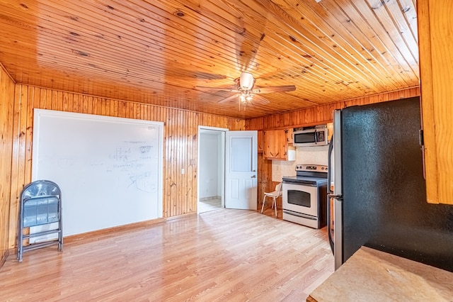 1204 Tinker St, Seagraves, TX 79359 - kitchen with stainless steel appliances, a ceiling fan, wood ceiling, wooden walls, and light wood-type flooring