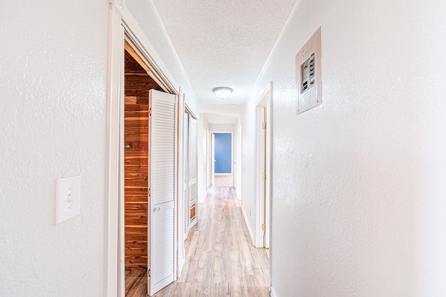 1204 Tinker St, Seagraves, TX 79359 - hallway with light wood-style floors, a textured wall, and a textured ceiling