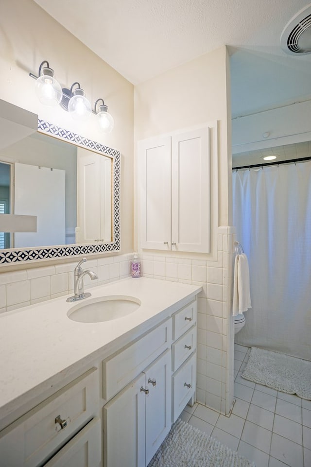 bathroom featuring a shower with shower curtain, vanity, tile walls, tile patterned flooring, and toilet