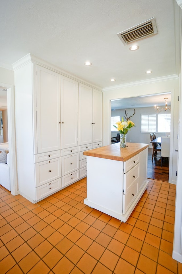 kitchen with white cabinets, butcher block counters, crown molding, and light tile patterned floors