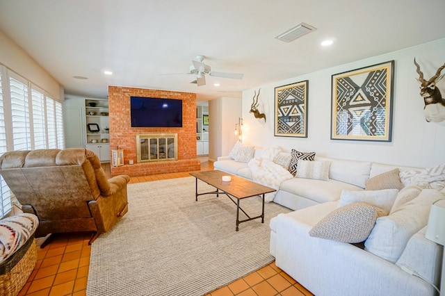 living room featuring a brick fireplace, built in features, ceiling fan, and light tile patterned flooring