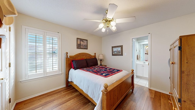 bedroom featuring a textured ceiling, wood finished floors, a ceiling fan, baseboards, and ensuite bath