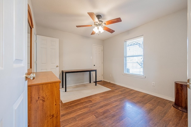 interior space with a ceiling fan, baseboards, and wood finished floors