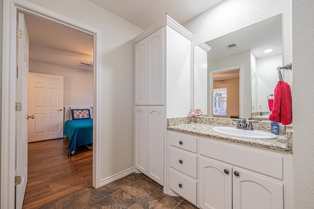 bathroom with baseboards, visible vents, wood finished floors, ensuite bathroom, and vanity