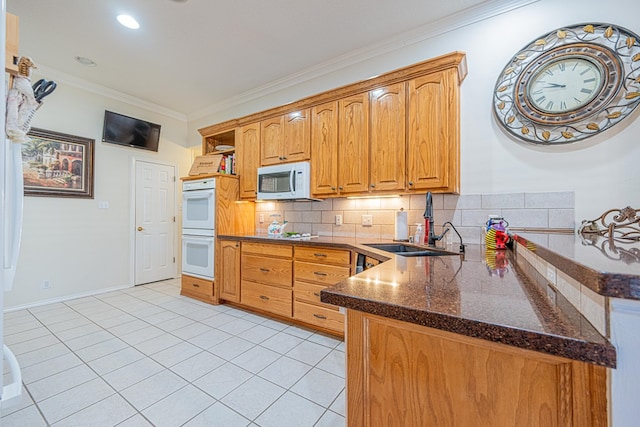 kitchen featuring white appliances, tasteful backsplash, a peninsula, crown molding, and a sink