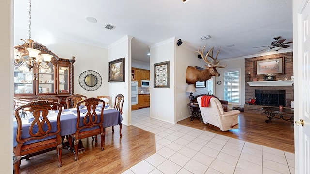 dining area with ceiling fan with notable chandelier, visible vents, a fireplace, and light tile patterned floors