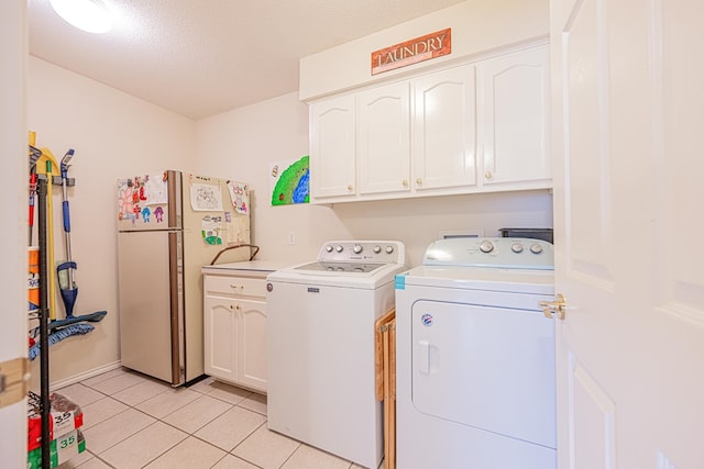 washroom featuring light tile patterned floors, a textured ceiling, independent washer and dryer, and cabinet space