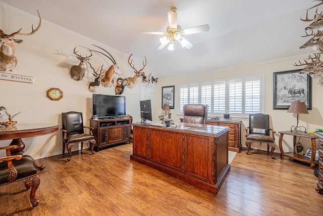 home office featuring crown molding, light wood finished floors, lofted ceiling, ceiling fan, and baseboards