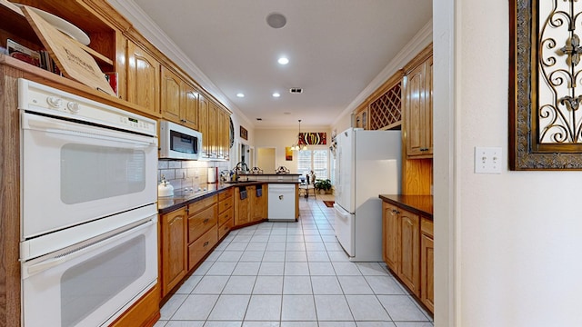 kitchen with dark countertops, decorative backsplash, ornamental molding, white appliances, and a peninsula