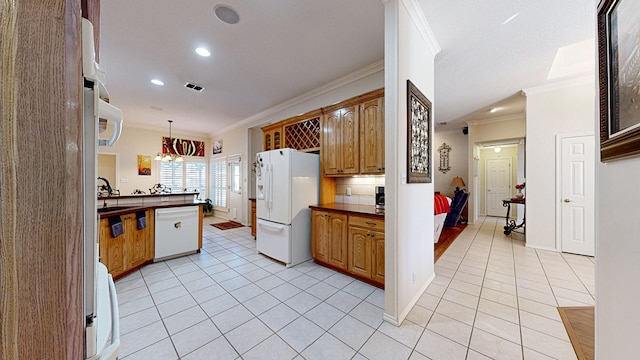 kitchen featuring dark countertops, white appliances, crown molding, and light tile patterned floors