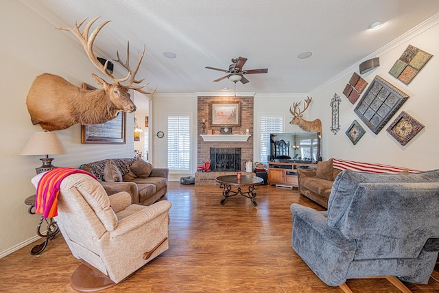 living area featuring a textured ceiling, a fireplace, wood finished floors, and crown molding