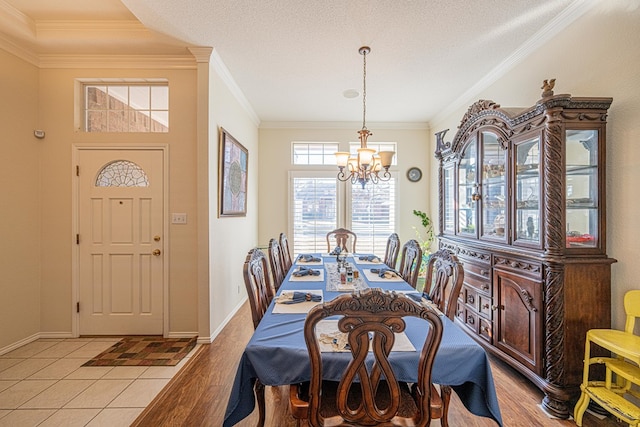 dining space featuring ornamental molding, light wood-type flooring, baseboards, and an inviting chandelier