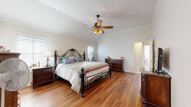 bedroom featuring lofted ceiling, light wood-style flooring, ornamental molding, and a ceiling fan