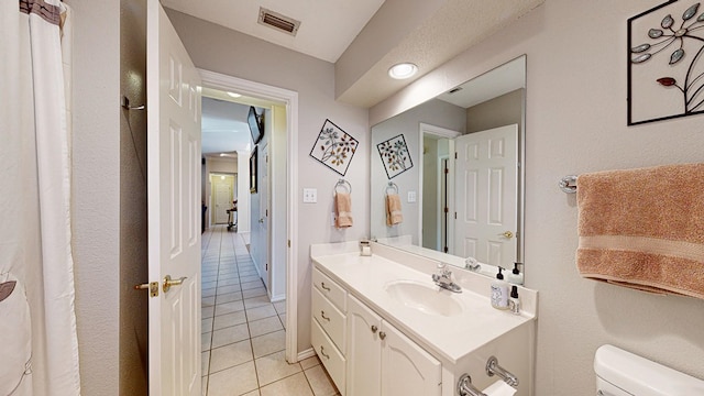 bathroom featuring visible vents, baseboards, toilet, tile patterned flooring, and vanity