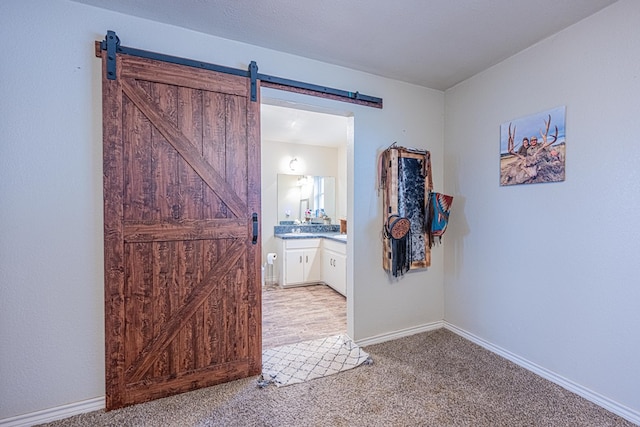 corridor with light carpet and a barn door