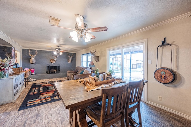 dining space with crown molding, wood-type flooring, and a fireplace